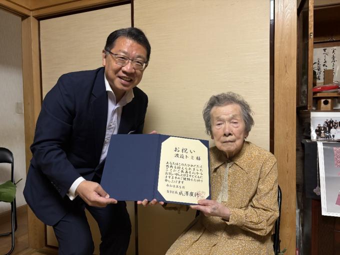 成澤区長が渡邉さんにお祝いの賞状を渡している様子