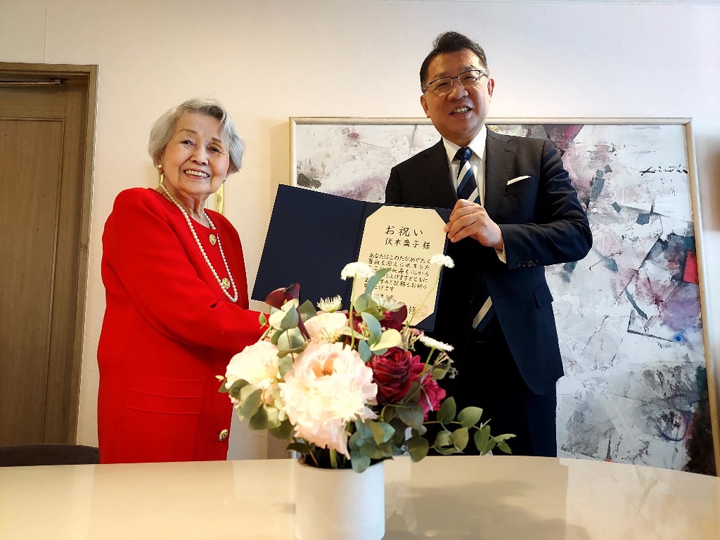 成澤区長が伏木さんにお祝い状を贈呈している様子