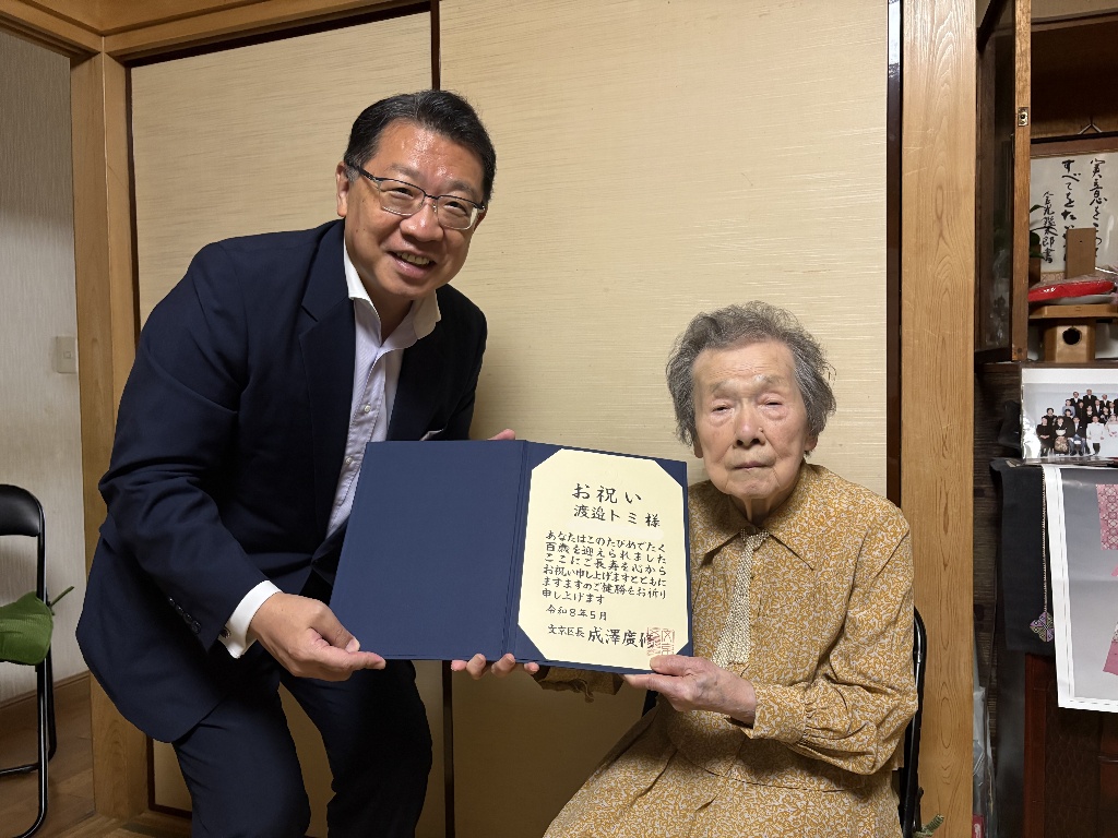成澤区長が渡邉さんにお祝いの賞状を渡している様子